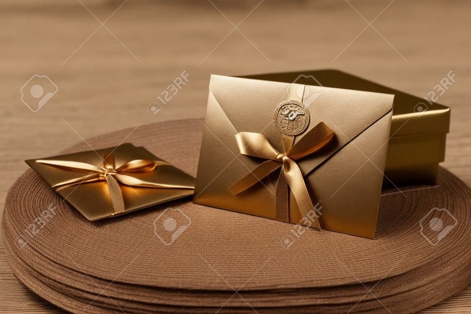 Bon podarunkowy, bon podarunkowy lub zniżka. zbliżenie na brązową kopertę z zaproszeniem ze wstążką i woskową pieczęcią, bon upominkowy, kartkę, kartkę z zaproszeniem na ślub