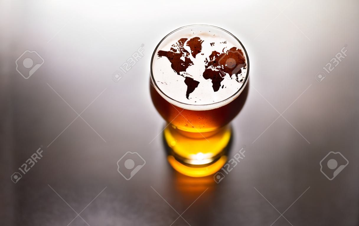 world map silhouette on foam in beer glass on black table. The continents shapes are altered ones from visibleearth.nasa.gov