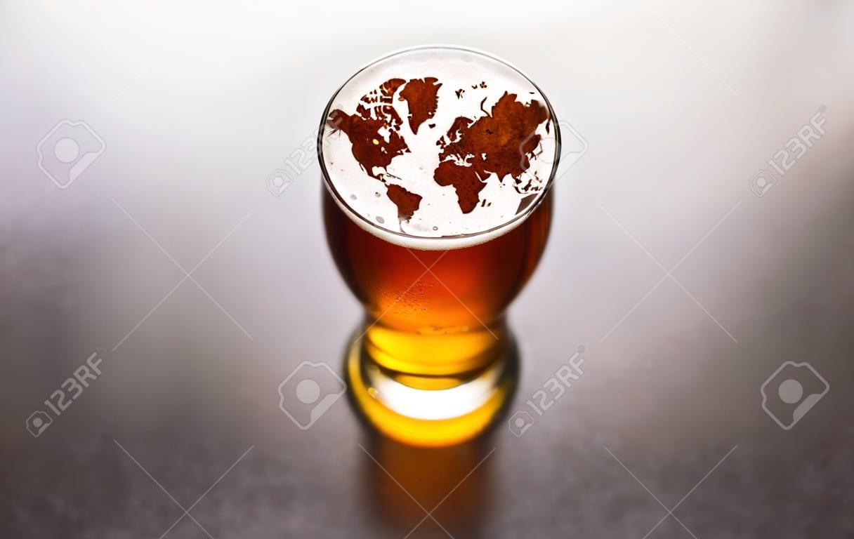 world map silhouette on foam in beer glass on black table. The continents shapes are altered ones from visibleearth.nasa.gov