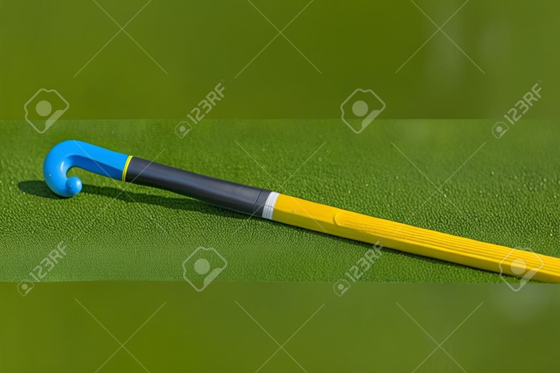 Field hockey stick and ball on green grass