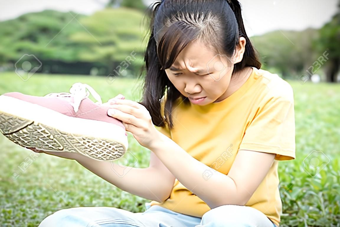 Une adolescente asiatique renifle ses baskets, tient une chaussure puante dans sa main avec du dégoût sur son visage, une odeur désagréable à cause du temps chaud ou après l'exercice, une petite fille avec une mauvaise odeur, de la saleté accumulée