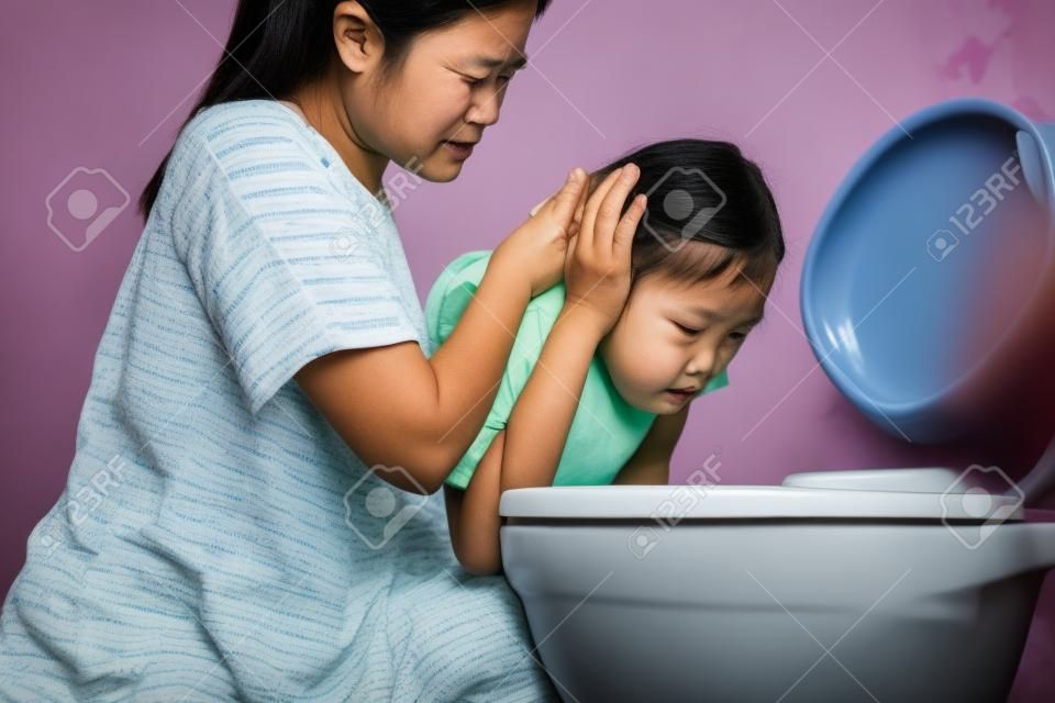 Sick asian child girl about to throw up,puking,vomiting into the toilet bowl,mother is taking care of her closely,suffering from indigestion,food poisoning,acute infectious diseases,gastritis problem