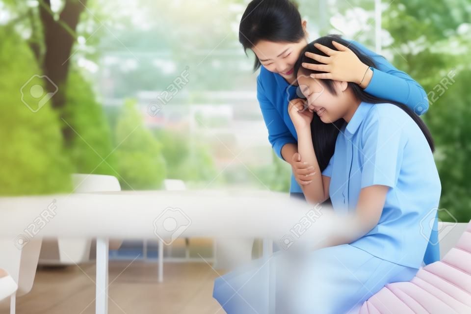 Asian woman is embracing comforting and caring for sad daughter in the school,depressed child girl sitting crying,loving mother support expressing empathy,speak have consoling,relationship concept