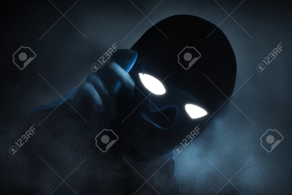Mysterious person showing white mask in the dark,Scary background for book cover