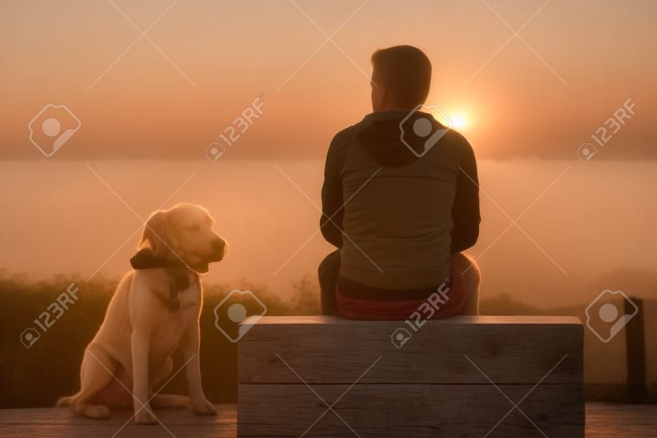 年輕男子與他的狗在日出。