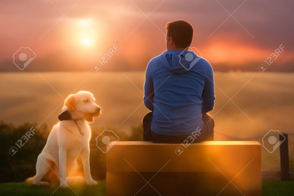 年輕男子與他的狗在日出。