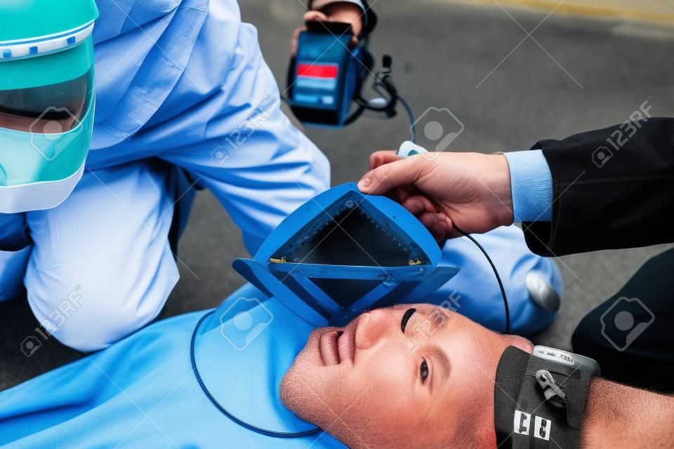 Elektrody defibrylatora. Ratownicy (lekarz i ratownik) reanimacji mężczyzna na ulicy.