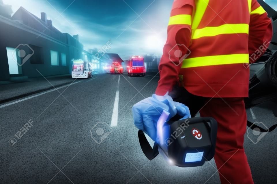 Hand des Arztes mit Defibrillator. Teams des Rettungsdienstes reagieren auf einen Verkehrsunfall.