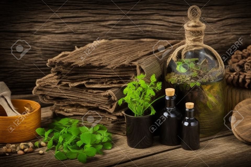 Tincture bottles, assortment of dry healthy herbs, old books, wooden mortar, sack of medicinal herbs. Herbal medicine.