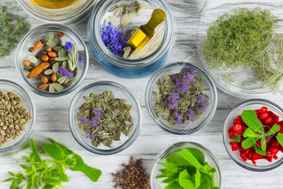 Bowls and jars of dry medicinal herbs. Healing herbs assortment, top view. Alternative medicine.