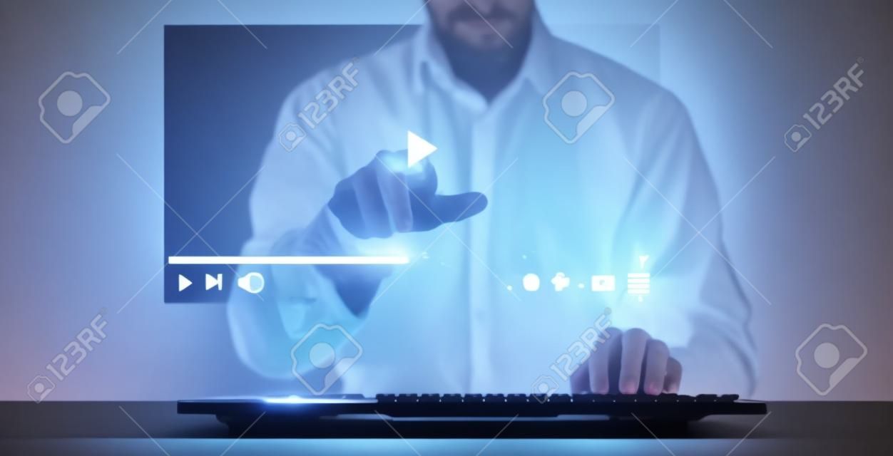 Man using keyboard for streaming online on virtual screeh hologram, watching video on internet, live concert, show or tutorial.