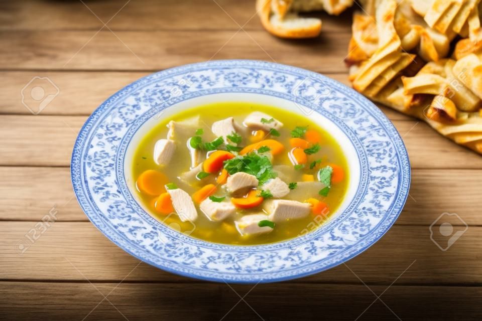 Chicken soup with vegetables on wooden table