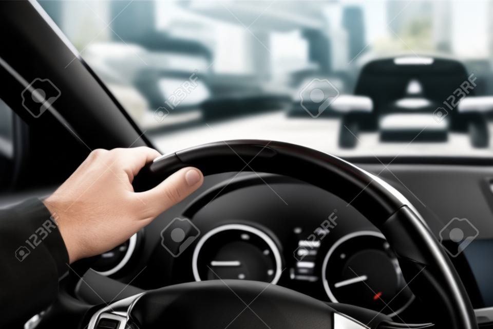 Car steering wheel with male hand. Man driving car in city concept.