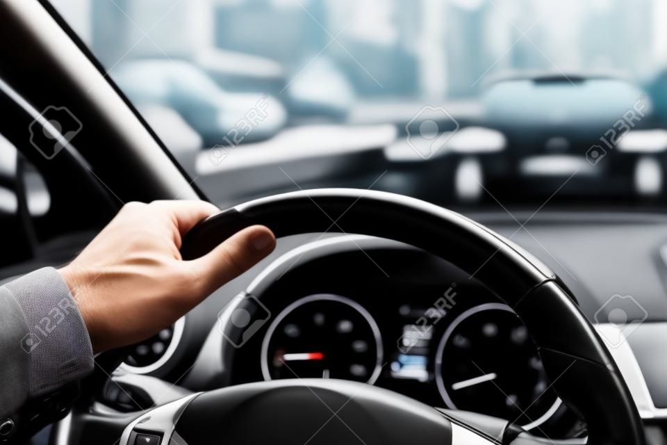 Car steering wheel with male hand. Man driving car in city concept.