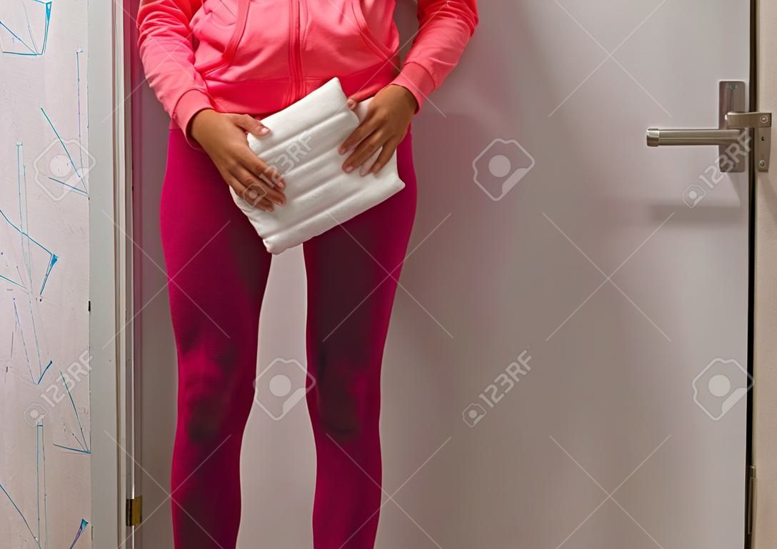 Incontinenza urinaria, giovane donna in un legging bagnato che tiene un pannolino bianco per adulti, problemi di salute imbarazzanti