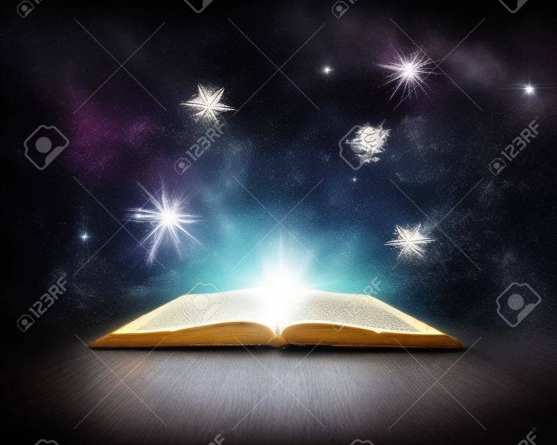 Vieux livre ouvert avec lumière magique et étoiles filantes Fond sombre