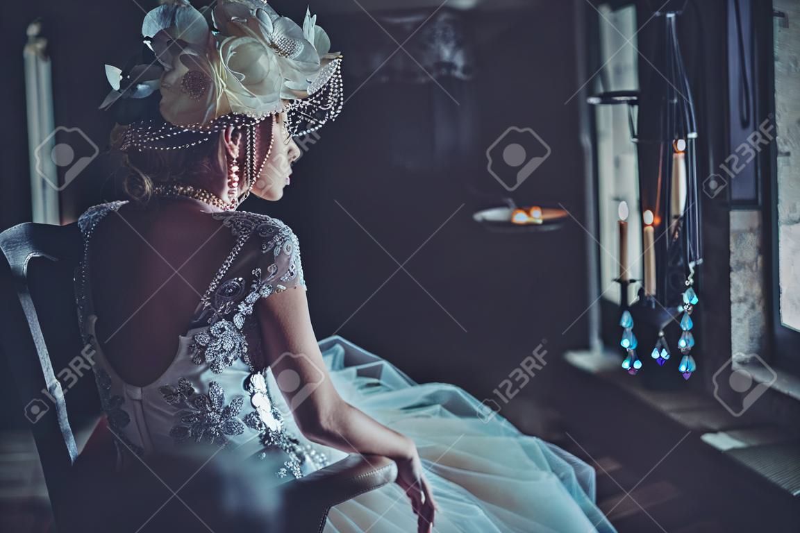 Beautiful bride sits on a chair. Luxury palace.