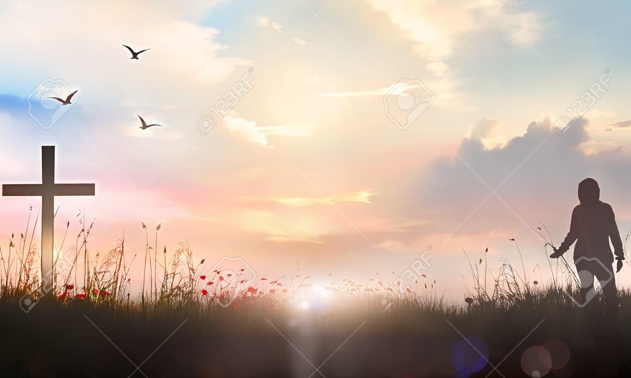 Praise and worship concept: Silhouette human standing and the cross on meadow sunset background