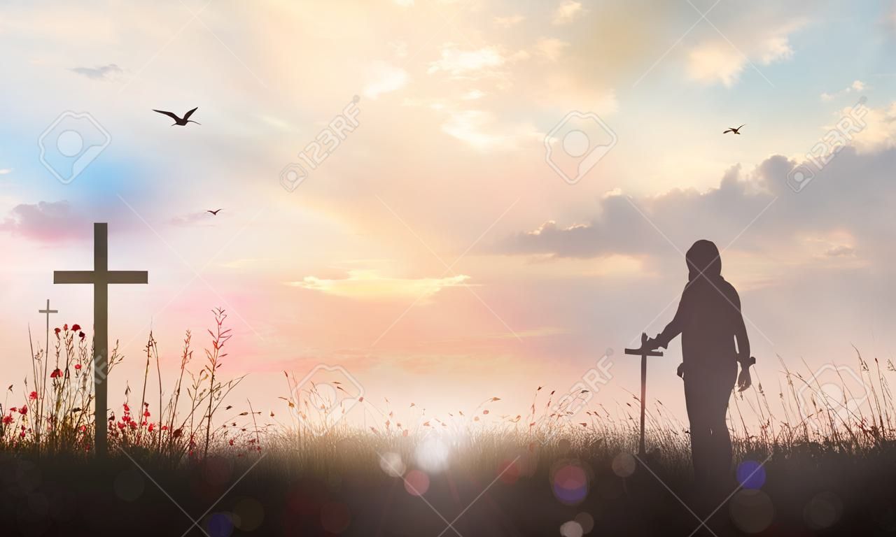 Concept de louange et d'adoration : silhouette humaine debout et la croix sur fond de coucher de soleil de prairie