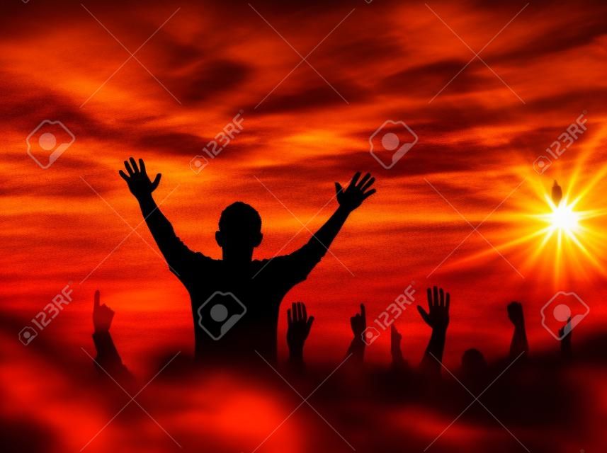 Praise and worship concept: Silhouette human raising hands to praying God on blurred cross with crown of thorn sunset background