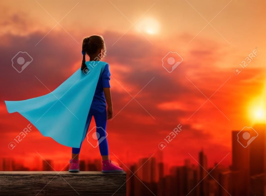 Kleine kind meisje speelt superheld. Kind op de achtergrond van zonsondergang hemel. Meisje macht concept