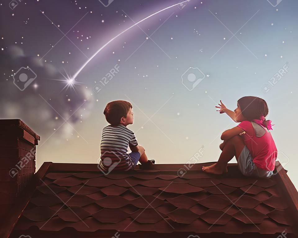 Zwei nette Kinder sitzen auf dem Dach und Blick auf die Sterne. Junge und Mädchen machen einen Wunsch durch eine Sternschnuppe zu sehen.
