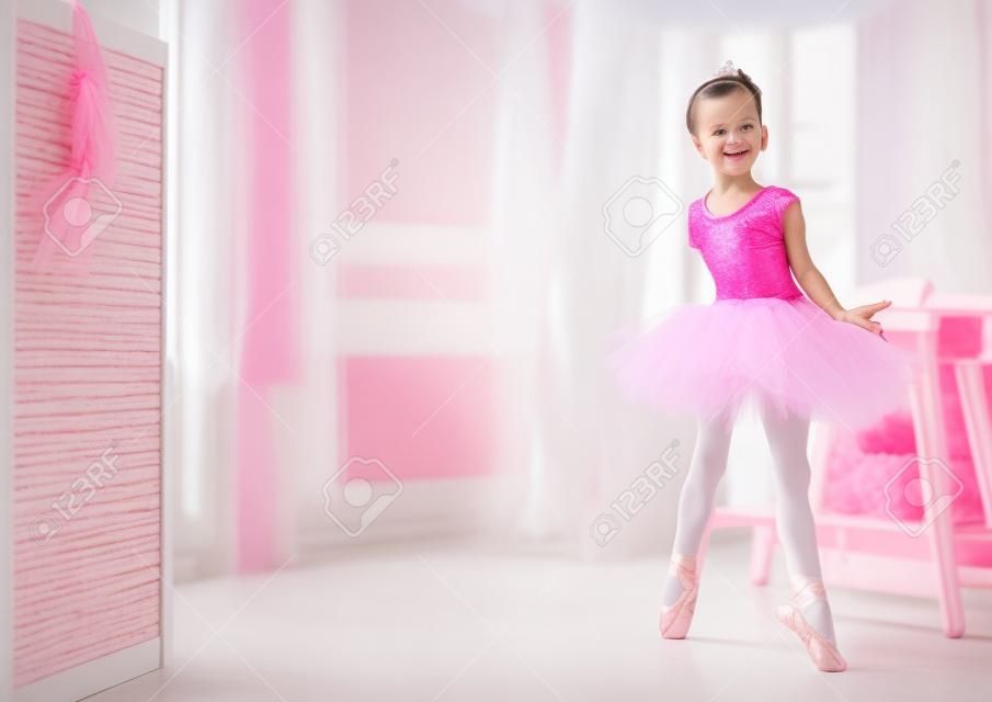 sueños de niña lindo de convertirse en una bailarina. La muchacha del niño en un baile tutú rosado en una habitación. El bebé está estudiando ballet.