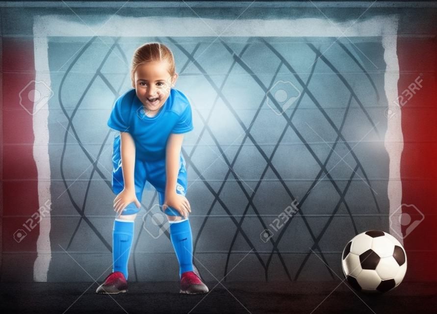 Niño lindo sueños de convertirse en un jugador de fútbol. La muchacha juega al fútbol.