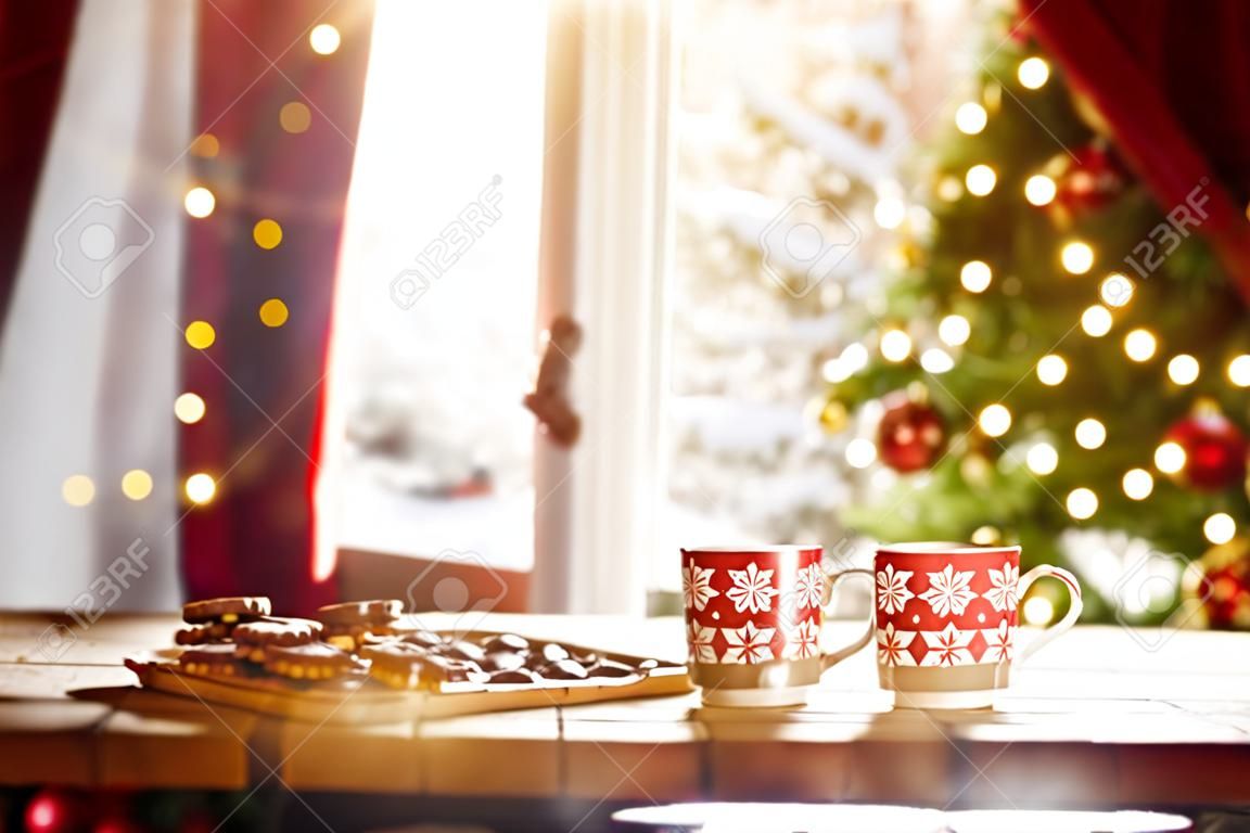 Wesołych Świąt i Wesołych Świąt. Czas rodzinnego przyjęcia herbacianego. Filiżanki ciepła herbata z Bożenarodzeniowymi ciastkami na drewnianym stole.