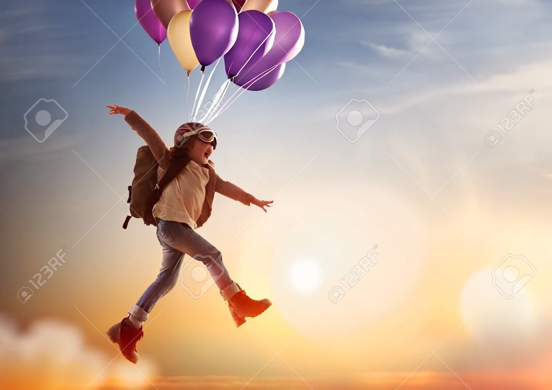 旅行の夢!夕日の背景に風船で飛んでの子。