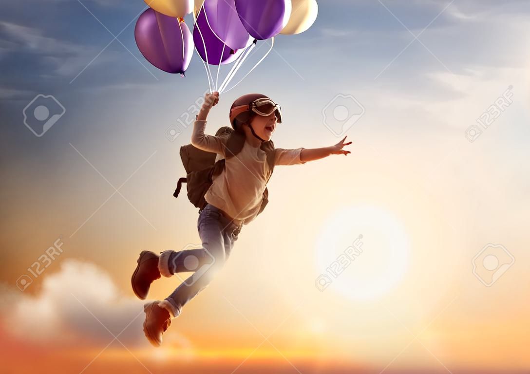旅行の夢!夕日の背景に風船で飛んでの子。