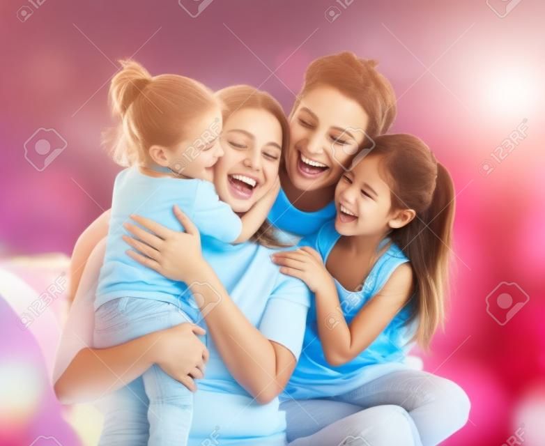 Szczęśliwego dnia Matki! Dwoje dzieci córki z ojcem pogratulować mamie. Mama, tata i dziewczęta śmieją i przytulanie. święto rodziny i wspólnoty.