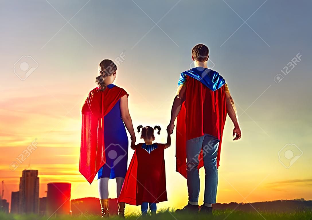 Mother, father and their daughters are playing outdoors. Mommy, daddy and children girls in an Superhero's costumes. Concept of super family.