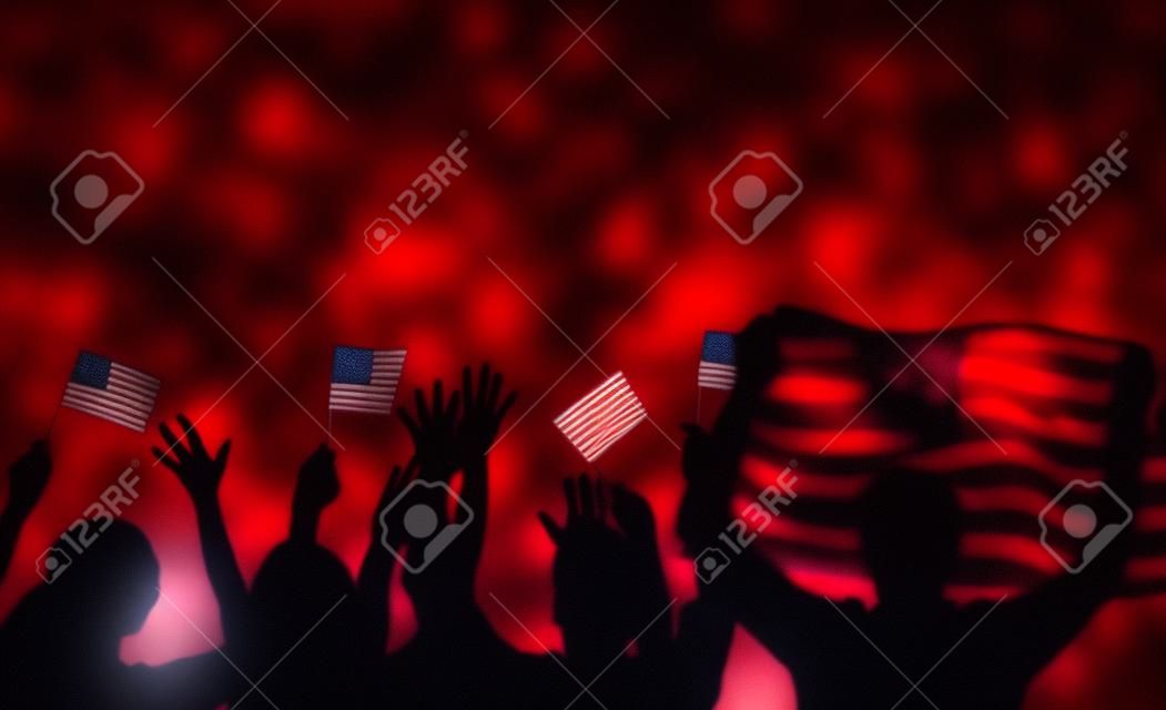 Patriotic holiday. Silhouettes of people holding the Flag of USA. America celebrate 4th of July.