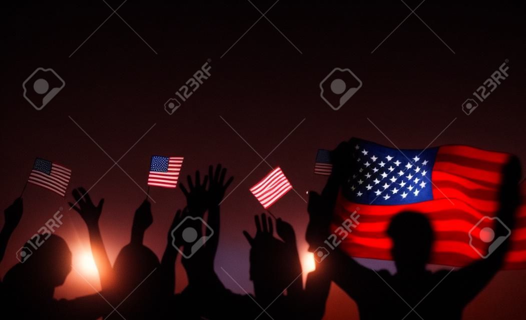 Feriado patriótico. Silhuetas de pessoas segurando a bandeira dos EUA. A América celebra 4 de julho.