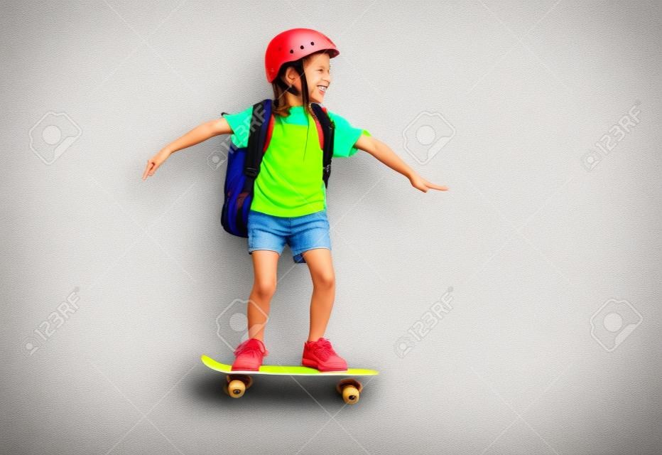 Childhood and happy time! Cute child with skateboard on color paper wall background. Kid with backpack. Girl ready to study.