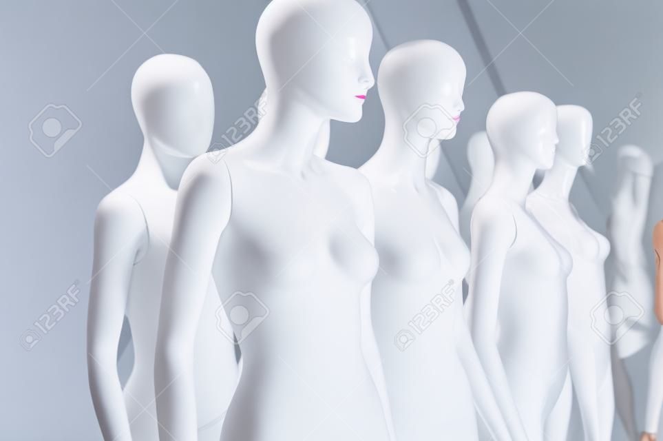 Eight white store fashion female mannequins displayed grouped together