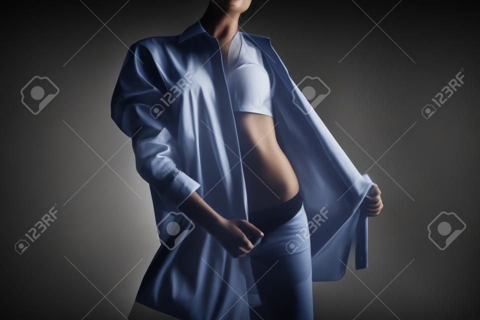 Photo of woman taking off mens shirt on black background