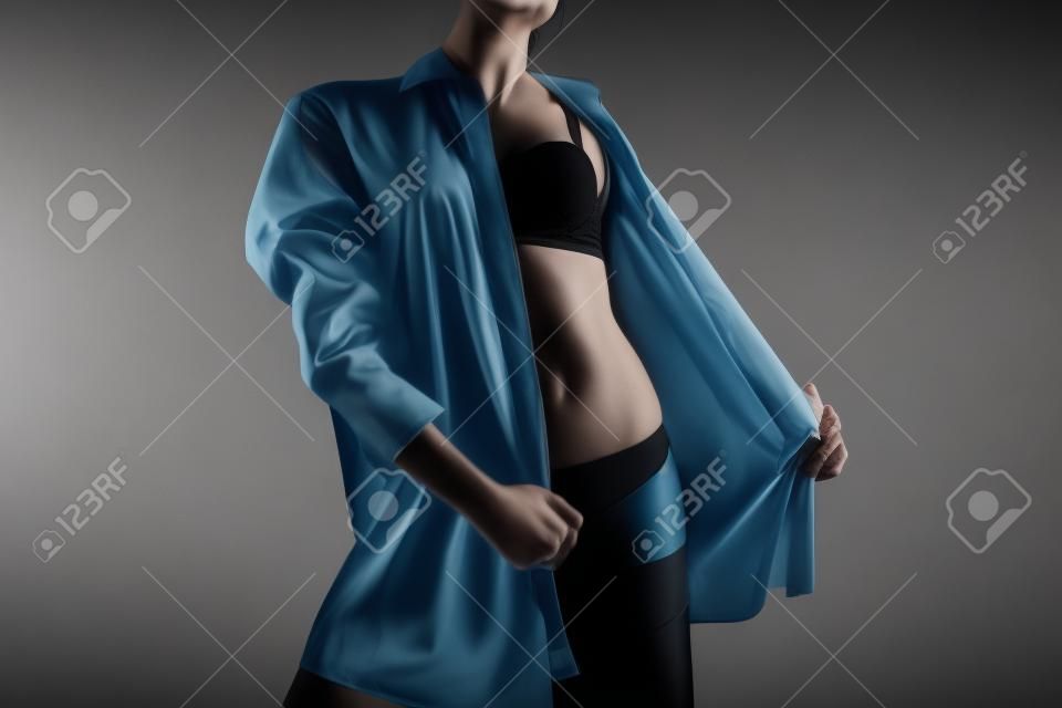 Photo of woman taking off mens shirt on black background
