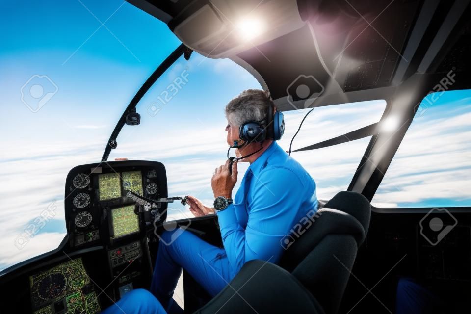 Shot of a mature Helicopter pilot using a headset while traveling in a helicopter, Business people traveling by helicopter