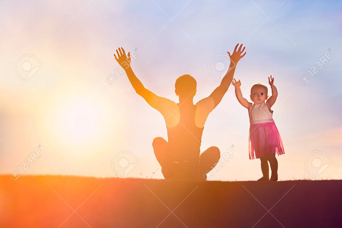 Father took the baby learn to walk at sunset.