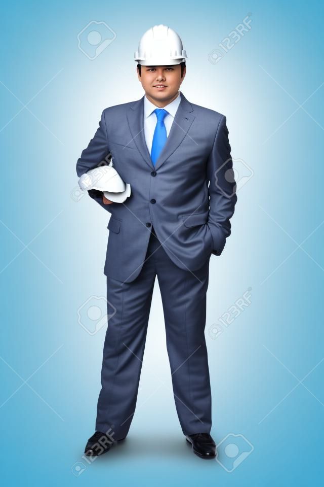 Serious businessman with helmet on head holding building projects in hand isolated on white
