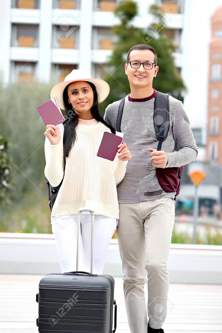 Happy multi-ethnic traveler couple holding passports and looking at camera. Sightseeing in Madrid, Spain.