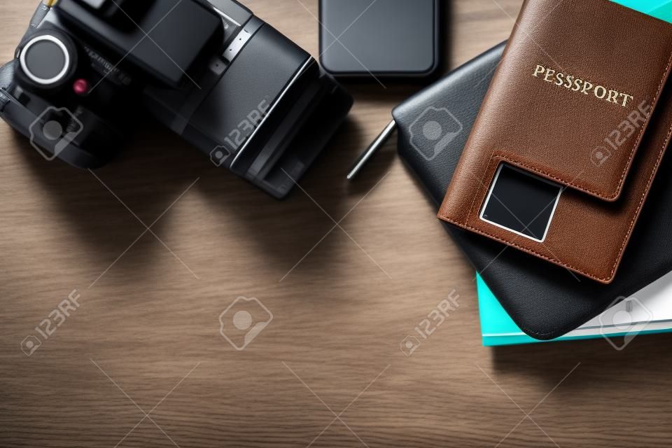top view of a desktop with a travel stuff consisting on a camera, a passport, a documents case, a phone and a map on a desk background - suitable for copy space