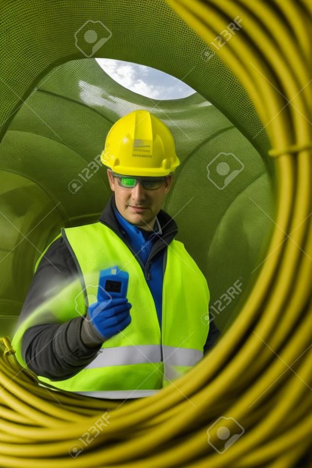 Superviseur inspection tout en regardant compteur geiger avec les fils du câble sur le site