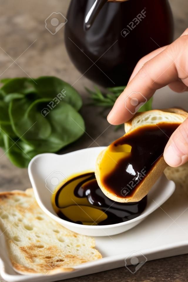 dipping baguette into balsamic vinegar and olive oil sauce