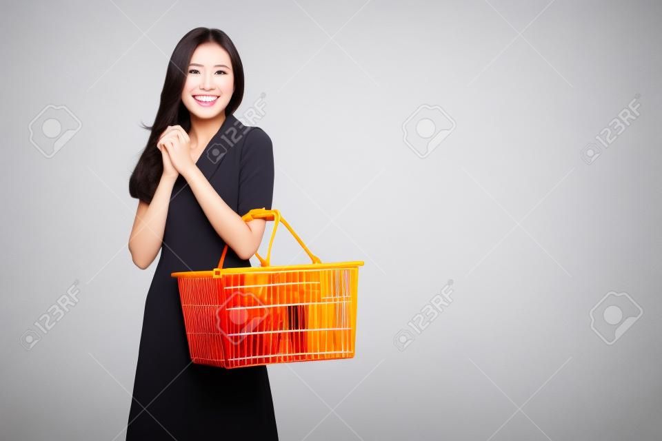 Bella donna asiatica sorridente e azienda carrello isolato su sfondo bianco