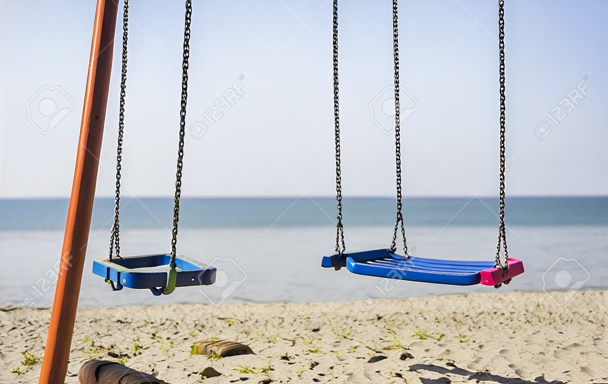 two empty kid swings on the Beach in a sunny day