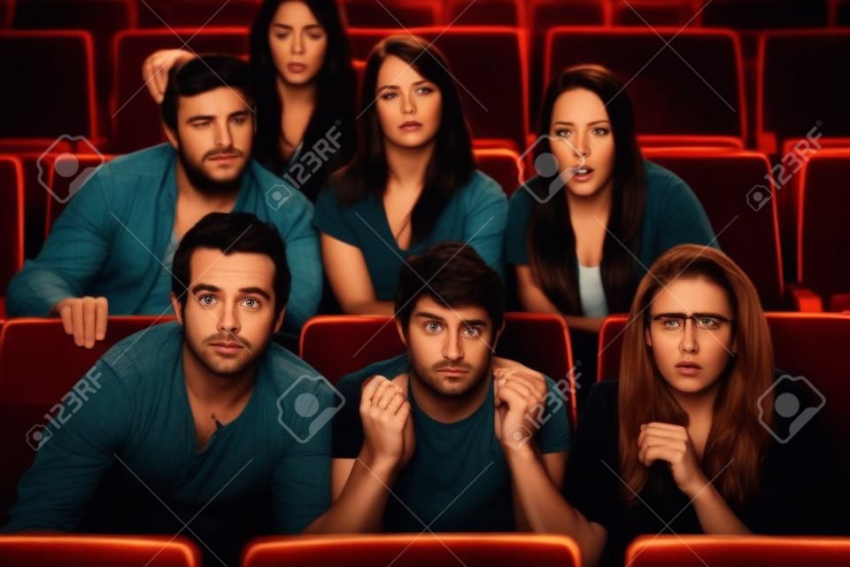 Grupo de personas asustadas viendo la película en un teatro