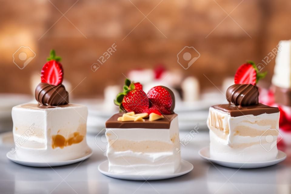 Auswahl an Desserts: Amandine, Baiser mit Schokolade und Erdbeeren, Karamellkuchen, in einem Restaurant, unscharfer Hintergrund